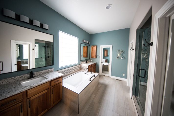 Image shows bathroom painter brooklyn specialist painted bathroom walls with dark blue color. Bathroom turned out to be nice with white vanity and wooden bathroom cabinets. Image was taken in September of 2019
