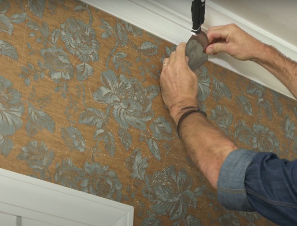 Image shows our apartment wallpaper installation professional gluing wallpaper for our client in his home. Image was taken in 2019 by our wallpaper installer.